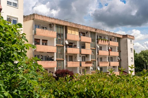 Ein vierstöckiger Wohnblock mit Balkonen im Grünen