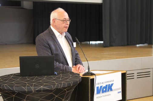Eine Mann steht an einem Pult und hält eine Rede