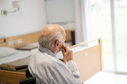 Senior im Pflegeheim Älterer Mann mit schütterem Haar schaut in seinem Zimmer im Pflegeheim Richtung Fenster